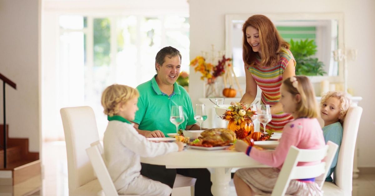 How I Feed My Family of 4 on $500 Per Month - picture of parents with two kids at dinner