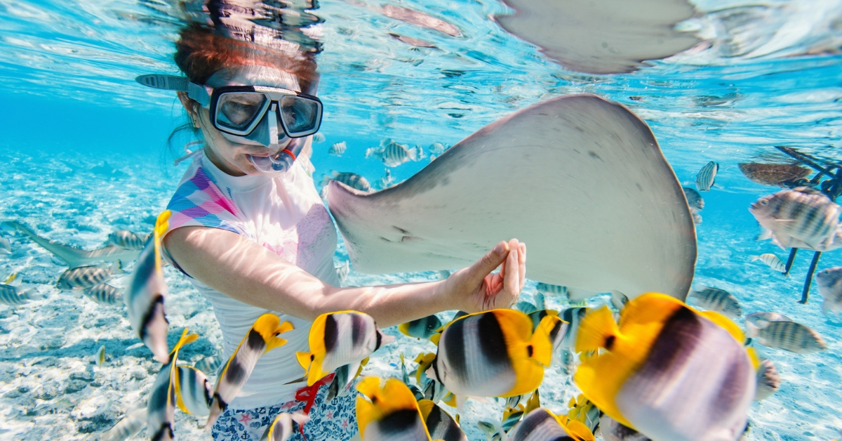 Atlas Travel Insurance Review - picture of woman snorkeling with ray and colorful fish