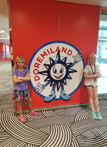 photo of two young girls by kids club sign