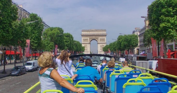 Photo of people on open air bus looking at Arc de Triomphe in Paris